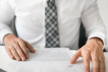 Açık renkli. Smartphone el genç işadamı sakallı. İşadamı'de ofis işleri tabloda belgelerle çalışmak. Mali belgeler iş. Yakın çekim. Bir dizüstü bilgisayar ile ofis işleri.