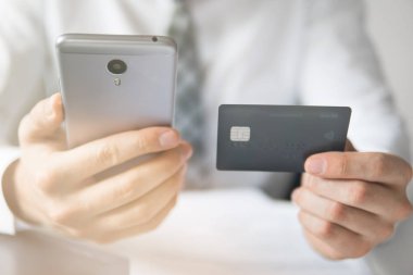 İşadamı bir smartphone ve kredi kartı online ödeme için kullanır. Gönderen e-posta, hareket eden telefon. Online alışveriş. Office iş kavramı. Beyaz arka plan. Telefonu kapatın. Işık sızıntıları