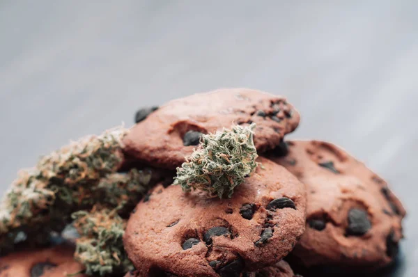 Botões de canábis num fundo preto. Cozimento com a adição de CBD. Doces com erva. Bolachas de chocolate com marijuana. Doces com cannabis . — Fotografia de Stock