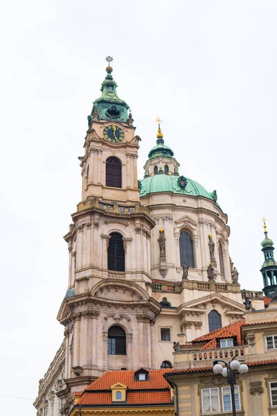 Praga con la Iglesia de San Nicolás, Mala Strana (Ciudad Menor de Praga) a través del arco de la torre Malostransky. Vista del colorido casco antiguo. Disparo vertical — Foto de Stock