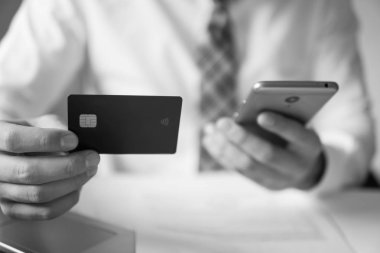 Akıllı telefon ve Internet ticareti. Online Döviz Alım Satım ticaret. Genç işadamı onun elinde banka kredi kartıyla. Malların online ödeme. Telefon aracılığıyla online ödeme.