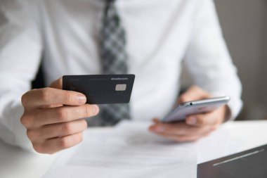 Genç işadamı onun elinde banka kredi kartıyla. Akıllı telefon ve Internet ticareti. Malların online ödeme. Online Döviz Alım Satım ticaret. Telefon aracılığıyla online ödeme.