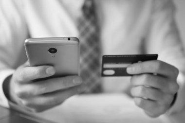 Akıllı telefon ve Internet ticareti. Online ödeme telefon aracılığıyla. Genç işadamı onun elinde banka kredi kartıyla. Malların online ödeme. Online Döviz Alım Satım ticaret.
