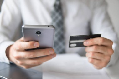 Online Döviz Alım Satım ticaret. Akıllı telefon ve Internet ticareti. Genç işadamı onun elinde banka kredi kartıyla. Online ödeme telefon aracılığıyla. Malların online ödeme.