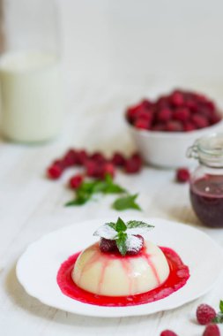 Dikey vurdu. Yaz tatlı. Açık renkli. Yakın çekim. Uçan pudra şekeri. Ahududu ve nane ile panakota. Dikey vurdu.