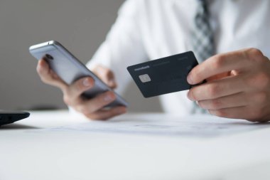 Online Döviz Alım Satım ticaret. Akıllı telefon ve Internet ticareti. Malların online ödeme. Online ödeme telefon aracılığıyla. Onun elinde banka kredi kartıyla genç işadamı.