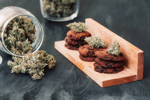 Cannabis knoppar på en svart bakgrund. Bakning med tillägg av Cbd. godis med ogräs. Choklad cookies med marijuana. Godis med cannabis. Kopia-utrymme — Stockfoto