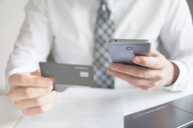 Online ödeme telefon aracılığıyla. Genç işadamı onun elinde banka kredi kartıyla. Online Döviz Alım Satım ticaret. Akıllı telefon ve Internet ticareti. Malların online ödeme.