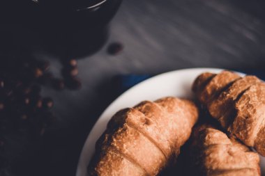 Tatlı ve kahve çekirdekleri. Moody renk dostum. Kahvaltı kavramı. Taze kruvasan ve kahve siyah bir arka plan üzerinde makro çekim.