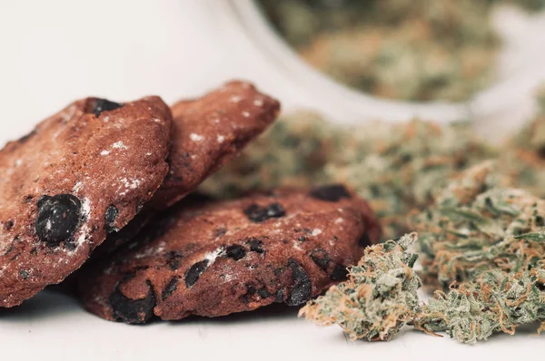 Sweets with cannabis. Cannabis buds on a black background. Baking with the addition of CBD. Sweets with weed. Chocolate cookies with marijuana. — Stock Photo, Image