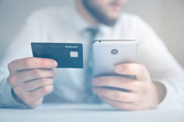 Akıllı telefon ve Internet ticareti. Malların online ödeme. Online ödeme telefon aracılığıyla. Genç işadamı onun elinde banka kredi kartıyla. Online Döviz Alım Satım ticaret.