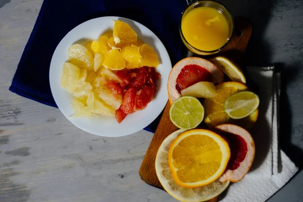 Verschiedene Zitrusfrüchte in Scheiben geschnitten Orange, Zitrone, Limette, Grapefruit, Pomelo und ein Glas Orangensaft. auf einem hölzernen — Stockfoto