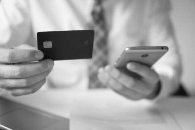 Online Döviz Alım Satım ticaret. Genç işadamı onun elinde banka kredi kartıyla. Malların online ödeme. Online ödeme telefon aracılığıyla. Akıllı telefon ve Internet ticaret.