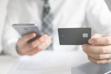 Çevrimiçi ödemeler telefonla. Malların internetten ödenmesi. Akıllı telefon ve internet ticareti. Elinde banka kartı olan genç bir iş adamı. Çevrimiçi döviz ticareti.