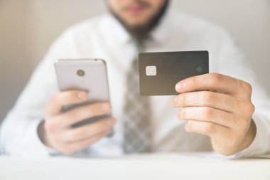 Akıllı telefon ve Internet ticareti. Online ödeme telefon aracılığıyla. Malların online ödeme. Online Döviz Alım Satım ticaret. Onun elinde banka kredi kartıyla genç işadamı.