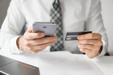 Akıllı telefon ve Internet ticareti. Genç işadamı onun elinde banka kredi kartıyla. Online ödeme telefon aracılığıyla. Malların online ödeme. Online Döviz Alım Satım ticaret.