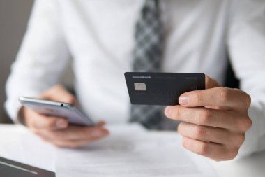 Online Döviz Alım Satım ticaret. Online ödeme telefon aracılığıyla. Genç işadamı onun elinde banka kredi kartıyla. Malların online ödeme. Akıllı telefon ve Internet ticaret.