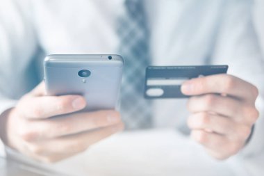 İşadamı bir smartphone ve kredi kartı online ödeme için kullanır. Beyaz arka plan. Office iş kavramı. Online alışveriş. Telefonu kapatın. Gönderen e-posta, hareket eden telefon. ışık sızıntıları