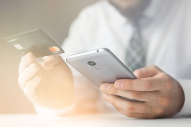 Genç işadamı onun elinde banka kredi kartıyla. Akıllı telefon ve Internet ticareti. Online ödeme telefon aracılığıyla. Malların online ödeme. Online Döviz Alım Satım ticaret.
