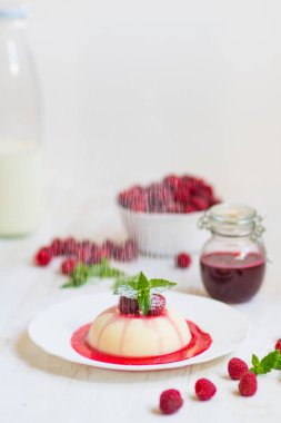 Dikey vurdu. Yaz tatlı. Açık renkli. Yakın çekim. Uçan pudra şekeri. Ahududu ve nane ile panakota.