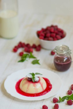 Açık renkli. Yakın çekim. Uçan pudra şekeri. Ahududu ve nane ile panakota. Dikey vurdu. Yaz tatlı.