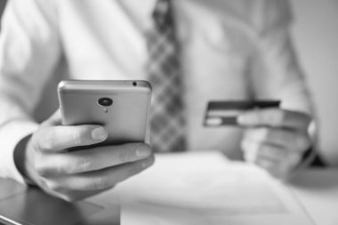 Genç işadamı onun elinde banka kredi kartıyla. Malların online ödeme. Online Döviz Alım Satım ticaret. Akıllı telefon ve Internet ticareti. Telefon aracılığıyla online ödeme.