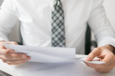 Smartphone el genç işadamı sakallı. İşadamı'de ofis işleri tabloda belgelerle çalışmak. Mali belgeler iş. Yakın çekim. Bir dizüstü bilgisayar ile ofis işleri. Açık renkli.