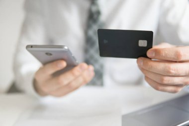 Malların online ödeme. Akıllı telefon ve Internet ticareti. Genç işadamı onun elinde banka kredi kartıyla. Online Döviz Alım Satım ticaret. Telefon aracılığıyla online ödeme.