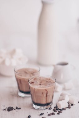 Yaz içeceği. Soğuk kahve süt ve çikolata. Dikey vurdu. Açık renkli. Buzlu kahve. Marshmelow ve kahve fasulye masanın üzerinde. Soğutma içki kavramı.