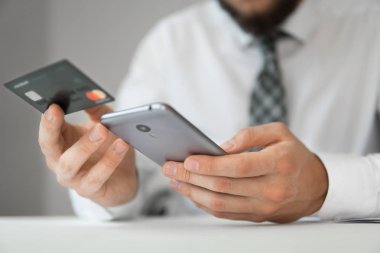 Genç işadamı onun elinde banka kredi kartıyla. Malların online ödeme. Online ödeme telefon aracılığıyla. Akıllı telefon ve Internet ticareti. Online Döviz Alım Satım ticaret.