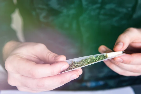 Man rolling a marijuana joint. Drug use. Close up . Drugs narcotic concept. Man preparing and rolling marijuana cannabis joint. Close up of addict lighting up marijuana joint with lighter. — Stock Photo, Image