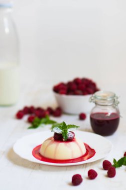 Açık renkli. Yakın çekim. Uçan pudra şekeri. Ahududu ve nane ile panakota. Dikey vurdu. Yaz tatlı.