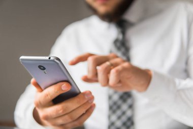 Bir dizüstü bilgisayar ile ofis işleri. Mali iş. Açık renkli. İş adamı iş bilgisayar ile ofis işleri tablo. Akıllı telefon elinde tutuyor. Genç işadamı sakallı.