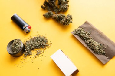 Üst Manzara. Sarı arka planda esrar tomurcukları. Kenevir tomurcukları için CBD ve THC. Blunt ve Lighters. Kopya uzayı için arkaplan. Kenevirin yasallaştırılması. Taze marihuana..