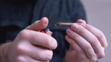 Adam bir esrar otu künt inişli çıkışlı. Esrar ortak çakmağı ile kapatın. esrar esrar künt haddeleme adam ışık yalıyor tonda renkli ışık sızıntıları.
