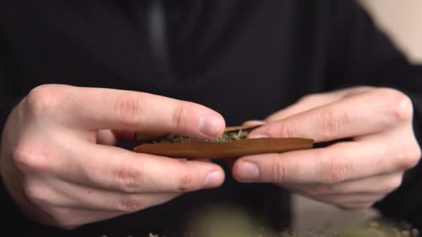 Un homme qui roule du cannabis contondant. L'homme roule une herbe à marijuana contondante. Fermez le joint de marijuana avec un briquet. lumière lèche couleur tonique fuites de lumière — Video