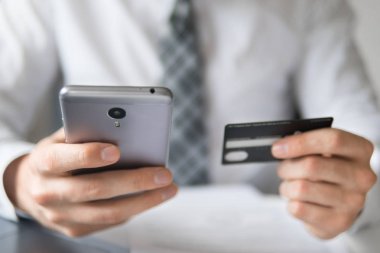 Akıllı telefon ve Internet ticareti. Online Döviz Alım Satım ticaret. Online ödeme telefon aracılığıyla. Malların online ödeme. Onun elinde banka kredi kartıyla genç işadamı.