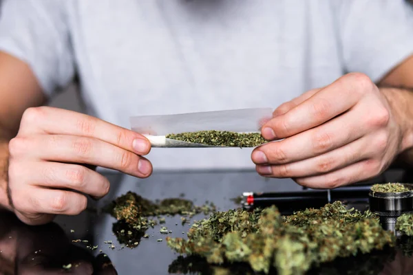 Omamné léky koncept. Člověče, přípravu a postupné konopí marihuana společné. Zblízka narkoman rozsvícení marihuana společné s lehčí. Muž, válcování jointa marihuany. Užívání drog. Detailní záběr. — Stock fotografie