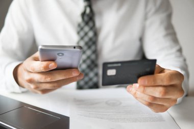 Genç işadamı onun elinde banka kredi kartıyla. Malların online ödeme. Online Döviz Alım Satım ticaret. Akıllı telefon ve Internet ticareti. Telefon aracılığıyla online ödeme.