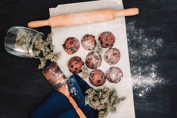 Doces com cannabis. Botões de canábis num fundo preto. Cozimento com a adição de CBD. Doces com erva. Bolachas de chocolate com marijuana. vista superior — Fotografia de Stock