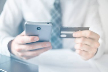 Online Döviz Alım Satım ticaret. Akıllı telefon ve Internet ticareti. Online ödeme telefon aracılığıyla. Malların online ödeme. Onun elinde banka kredi kartıyla genç işadamı.