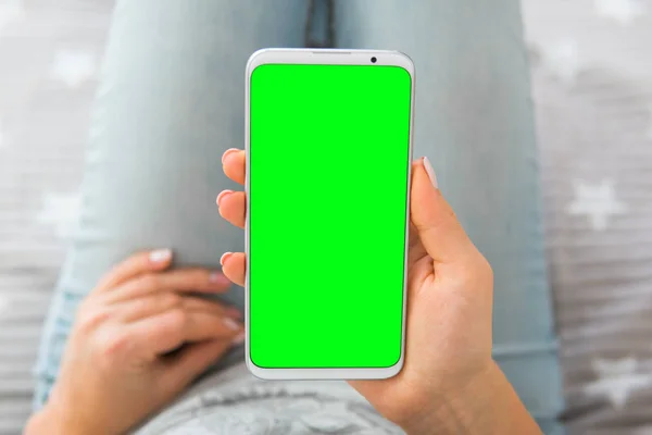 Mockup Green screen smartphone. key image of woman's hands holding mobile phone. close up. chroma