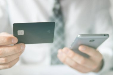 İşadamı bir smartphone ve kredi kartı online ödeme için kullanır. Office iş kavramı. Online alışveriş. Telefonu kapatın. Beyaz arka plan. Gönderen e-posta, hareket eden telefon. ışık sızıntıları
