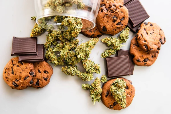 Behandeling van medische marihuana voor gebruik in levensmiddelen, witte Cookies met cannabis en toppen van marihuana op de tabel .background. Koekjes met cannabisbladeren Cbd. — Stockfoto