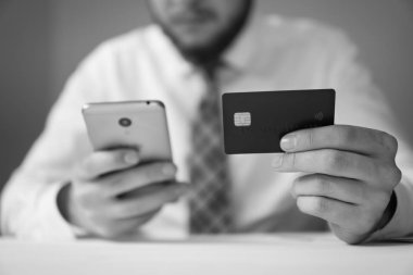Online ödeme telefon aracılığıyla. Akıllı telefon ve Internet ticareti. Online Döviz Alım Satım ticaret. Genç işadamı onun elinde banka kredi kartıyla. Malların online ödeme.