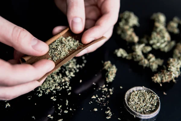 Hombre preparando y rodando marihuana marihuana conjunta. Un hombre rodando una marihuana roma. Primer plano de adicto iluminando marihuana con mechero. Concepto de uso de maceta. De cerca. . —  Fotos de Stock