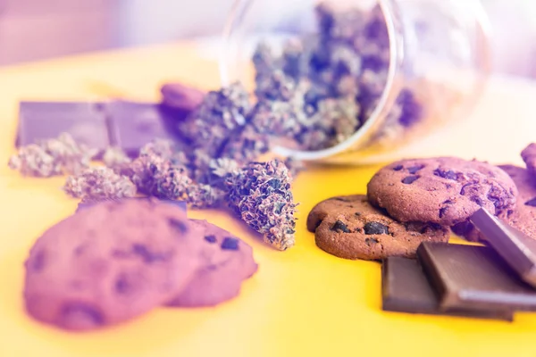 Cannabis CBD трава шоколад и печенье. Печенье и шоколад с марихуаной на столе. Лечение медицинской марихуаны для использования в пищевых продуктах, желтый фон. Утечки света — стоковое фото