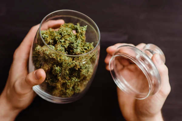 En massa marijuana. Ovanifrån. Närbild. Svart bakgrund. Begreppen legalisera ogräs. En bank med färska knoppar Cannabis i händerna på en man. — Stockfoto