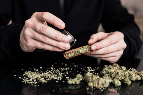 Primer plano de adicto iluminando marihuana con mechero. Hombre preparando y rodando marihuana marihuana conjunta . — Foto de Stock