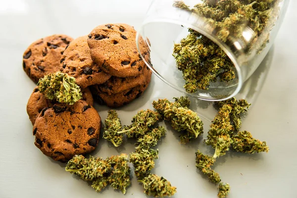Galletas con hierba de cannabis CBD. Galletas con cannabis y cogollos de marihuana sobre la mesa. Tratamiento de la marihuana medicinal para uso en alimentos, fondo blanco . —  Fotos de Stock